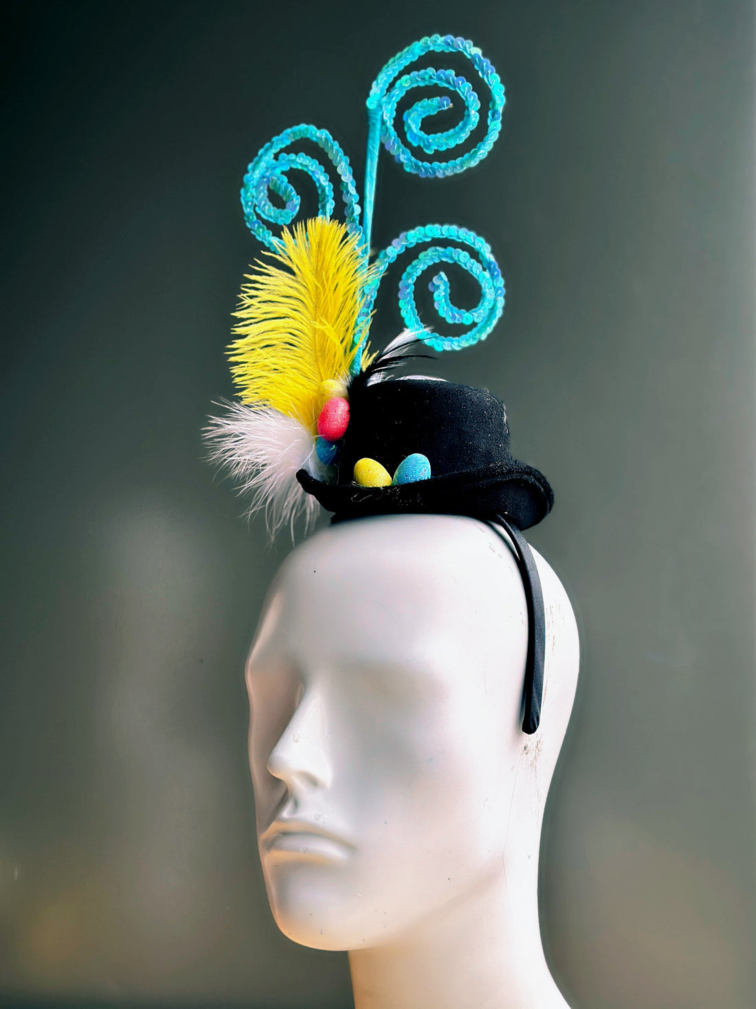 Black hat on a headband with easter eggs, feathers, and blue swirls.