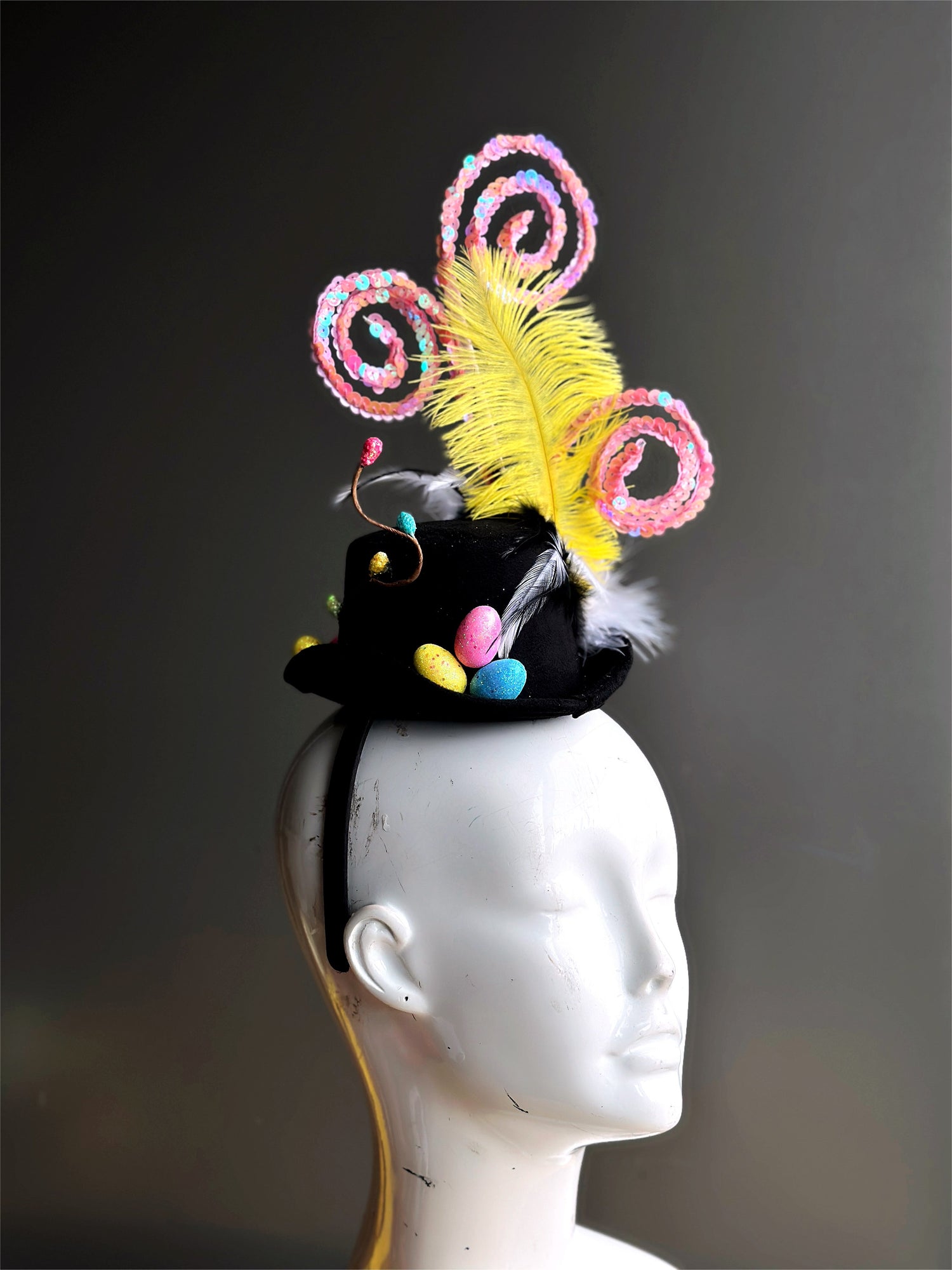 Black hat with colorful easter eggs, pink swirls, and feathers.
