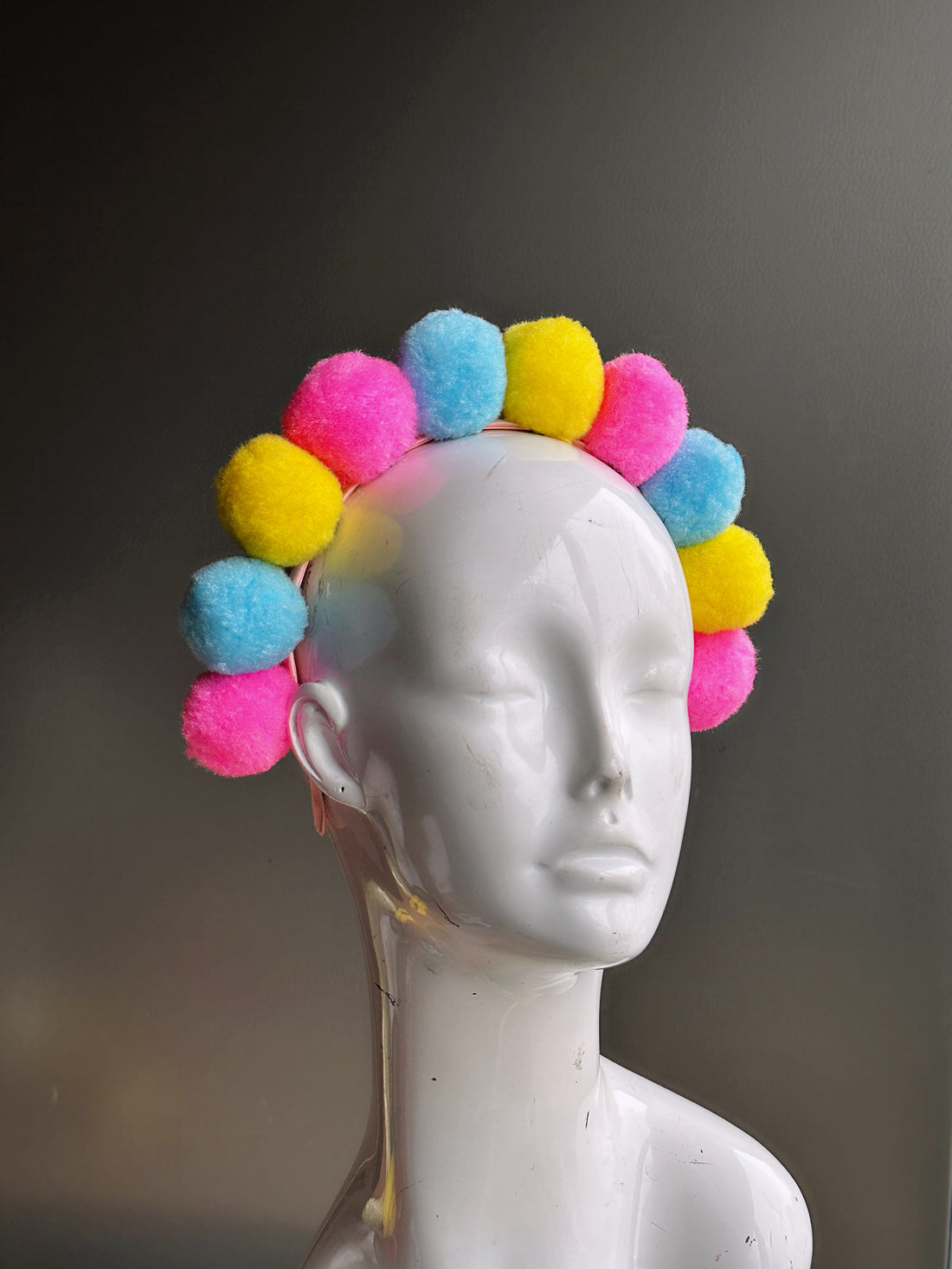 Fuzzy pompom balls in pink, blue, yellow on a pink headband
