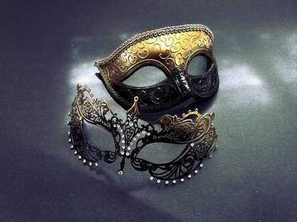 Black and gold couples masquerade masks with rhinestones—ornate lace filigree mask paired with a bold scrollwork design.