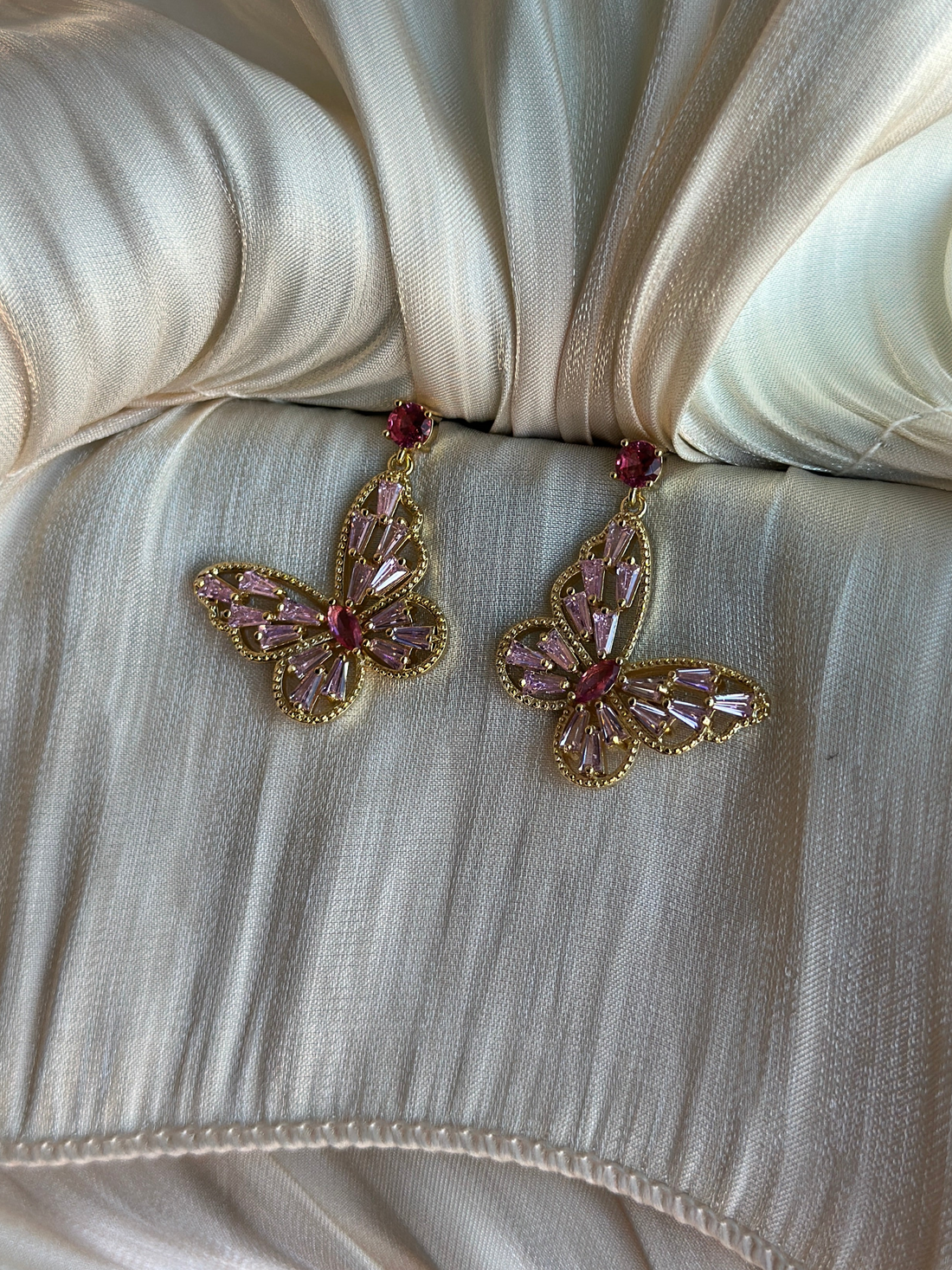 Pink and gold butterfly earrings styled for masquerade events, featuring lightweight non-tarnish metal and sparkly crystals.