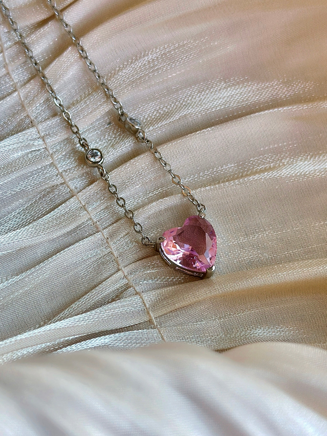Dainty silver masquerade necklace featuring a pink heart-shaped crystal, perfect for romantic and formal occasions.