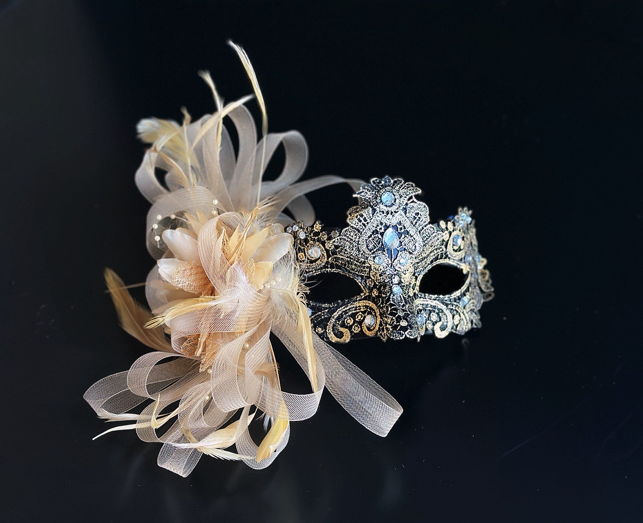 Gold lace masquerade mask with blue crystal details and champagne feather accent for weddings and formal masquerade events.