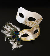 White masquerade mask set with gold detail and peacock feathers for elegant formal events.