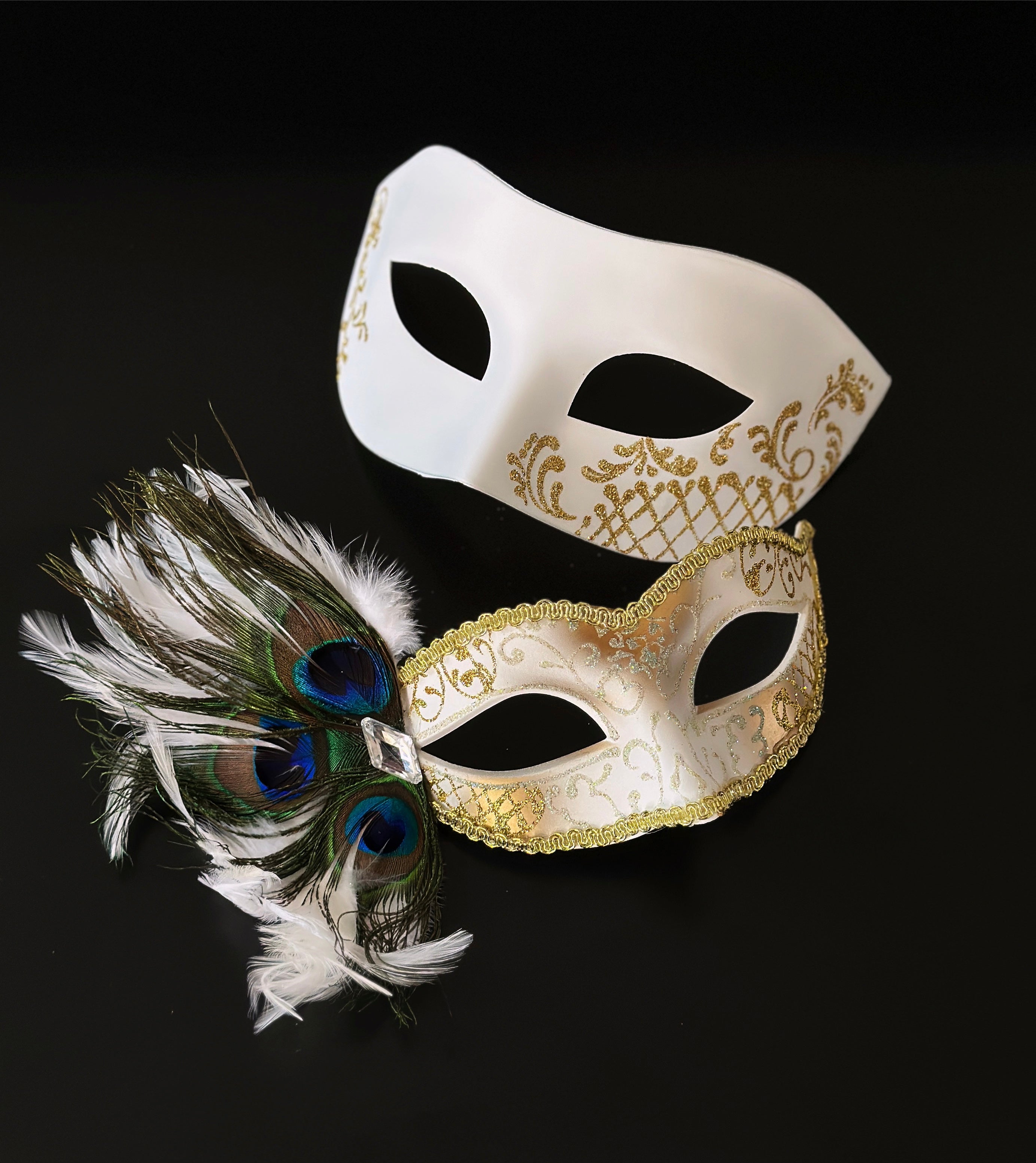 White masquerade mask set with gold detail and peacock feathers for elegant formal events.