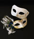 White masquerade mask set with gold detail and peacock feathers for elegant formal events.