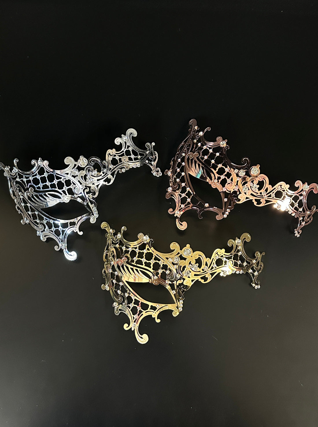 Elegant gold, silver, and bronze masquerade masks with intricate filigree detailing