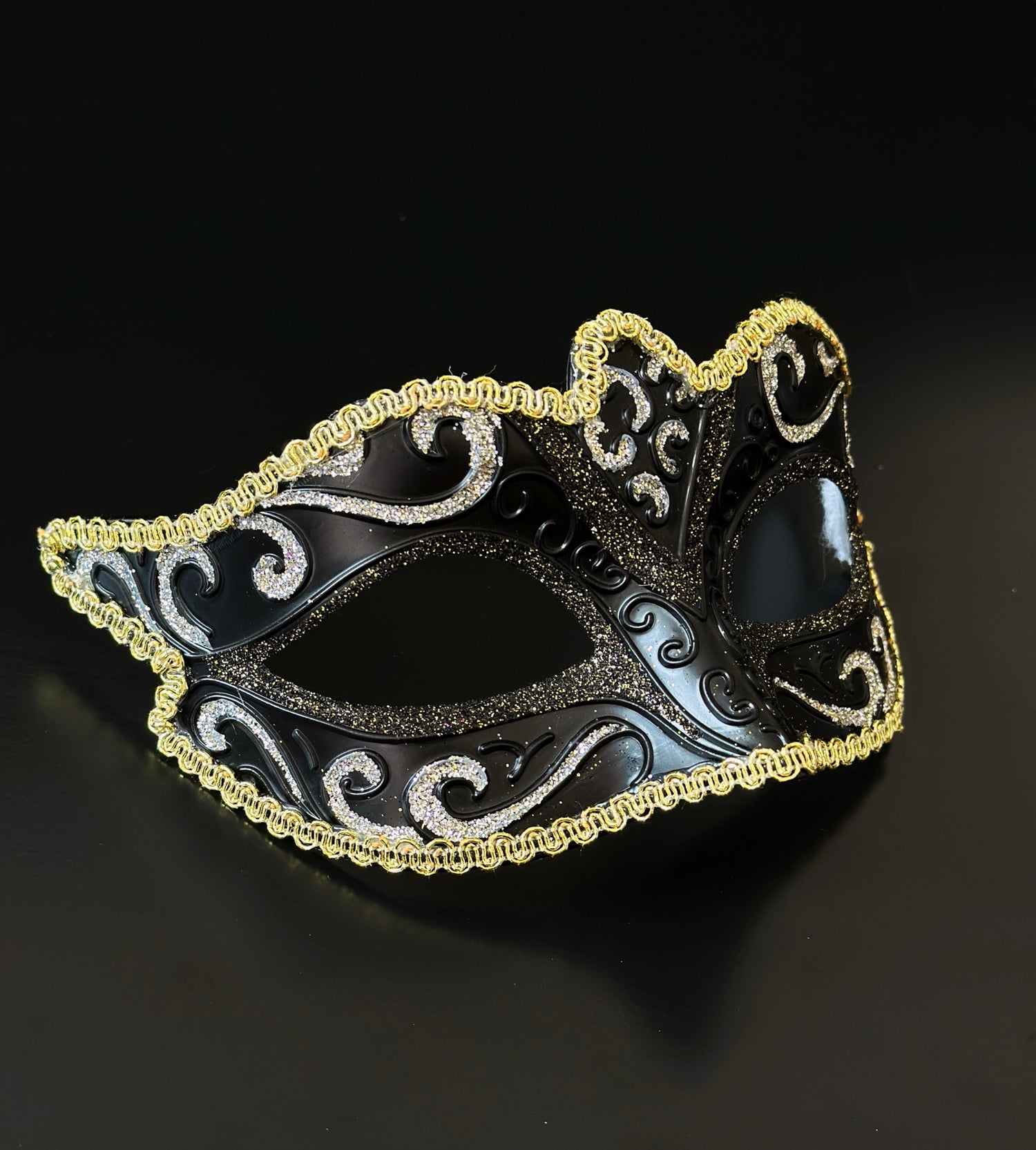 Black Venetian masquerade mask with gold trim and glitter scroll design for elegant formal events.