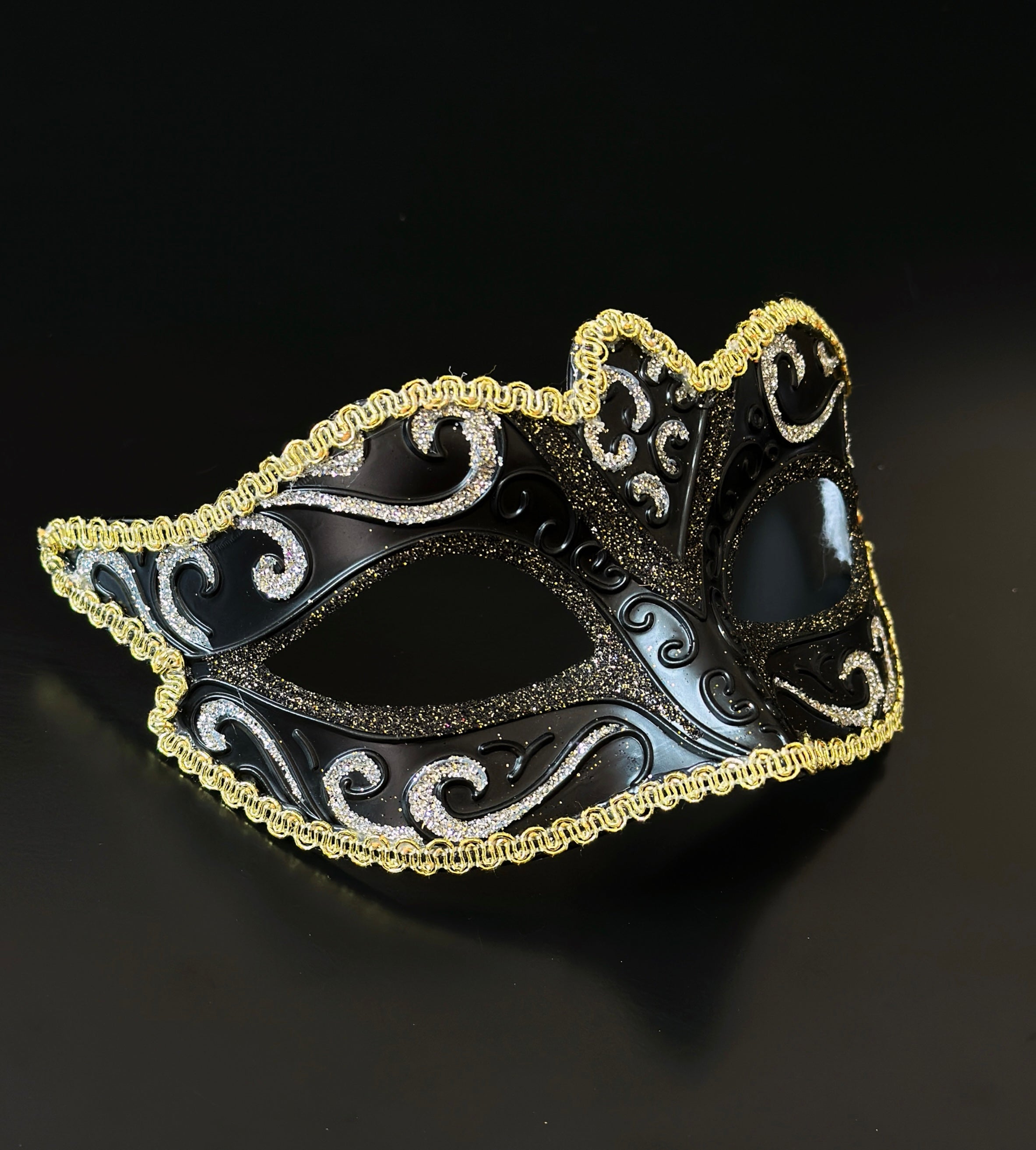 Black Venetian masquerade mask with gold trim and glitter scroll design for elegant formal events.