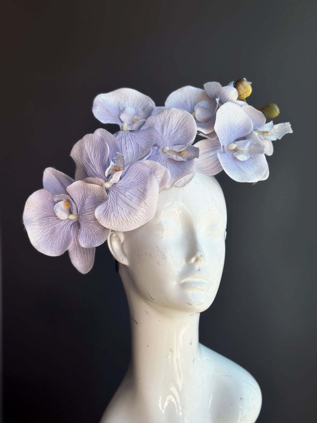Lavender orchid fascinator hat with oversized floral bouquet headpiece.