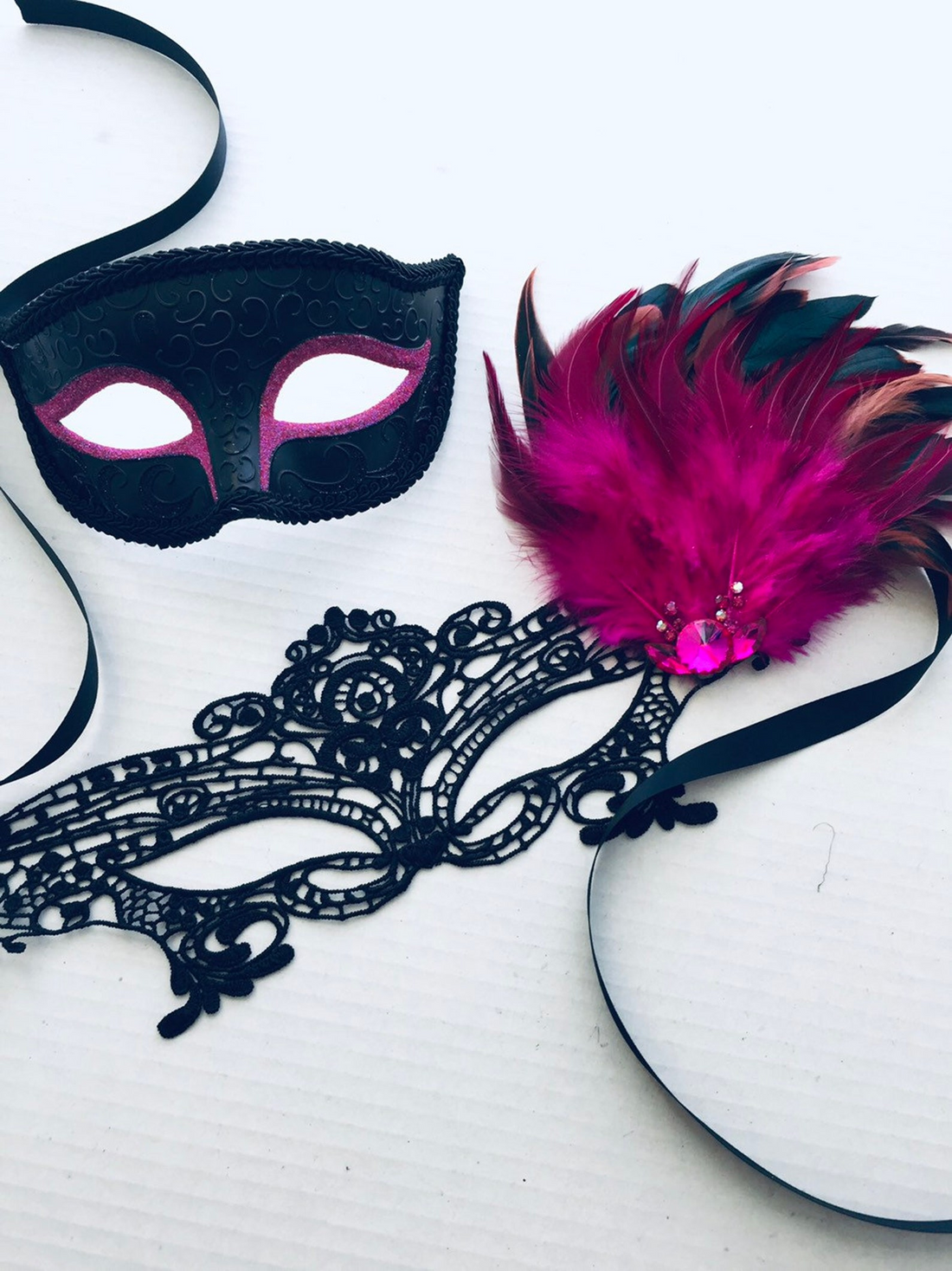Black and pink couples masquerade mask set with lace, feathers, and rhinestone details.