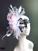 Patriotic masquerade mask with black filigree base, blue crystals, and dramatic red, white, and blue feather accents for women’s masquerade events.