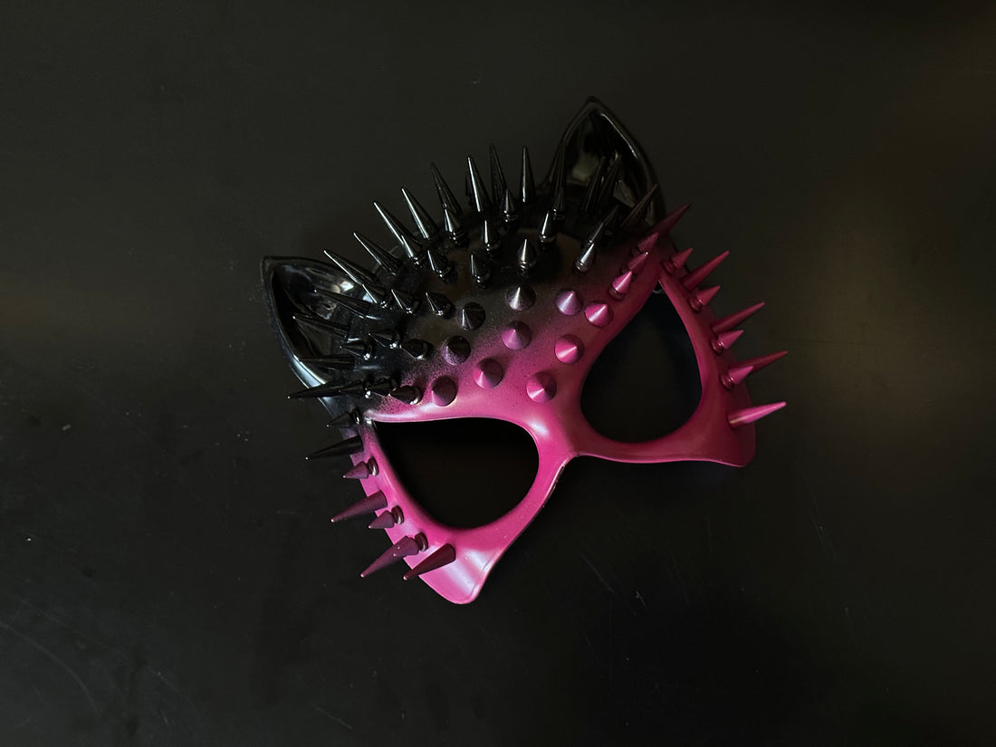 Pink and black spiked masquerade mask with cat ears and ombré finish, designed for bold Halloween or rave costumes.