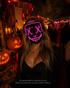 Pink Voltage LED light-up mask with glowing pink X eyes, stitched smile design, full-face shape, replaceable battery, and three lighting settings.
