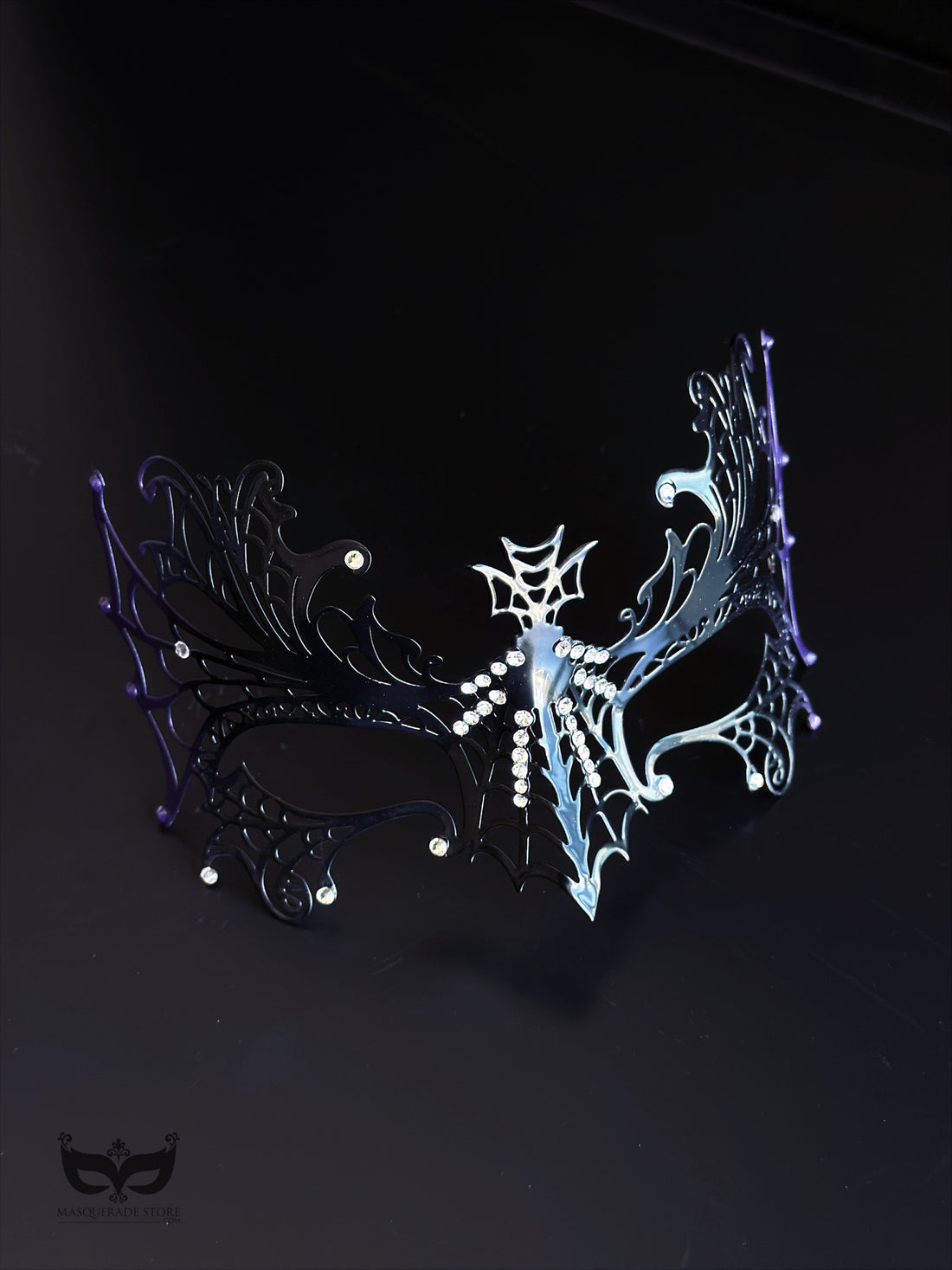 Purple and black spiderweb masquerade mask with gothic openwork filigree, rhinestone accents, purple web edges, and ribbon ties for costume events.