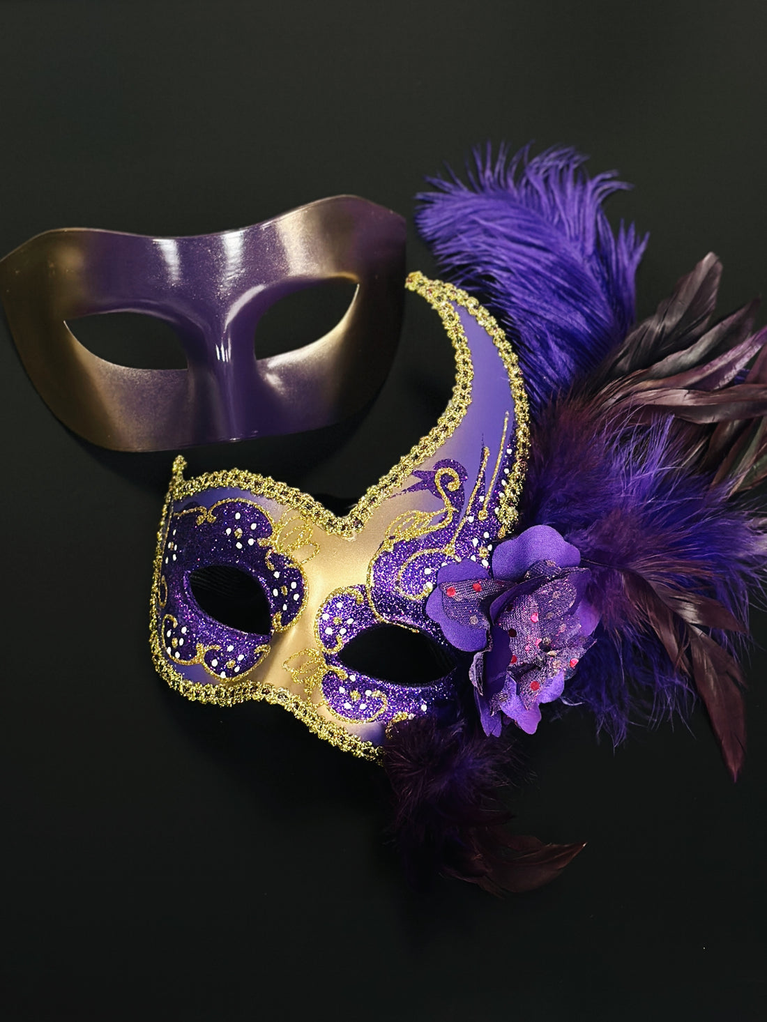 Purple and gold masquerade couples mask set, one with feathers and glitter detailing, perfect for masquerade balls, Mardi Gras, and Venetian parties.