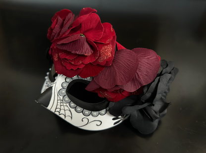 Sugar skull masquerade mask decorated with red and black roses, spiderweb detail, and a floral gothic crown.

