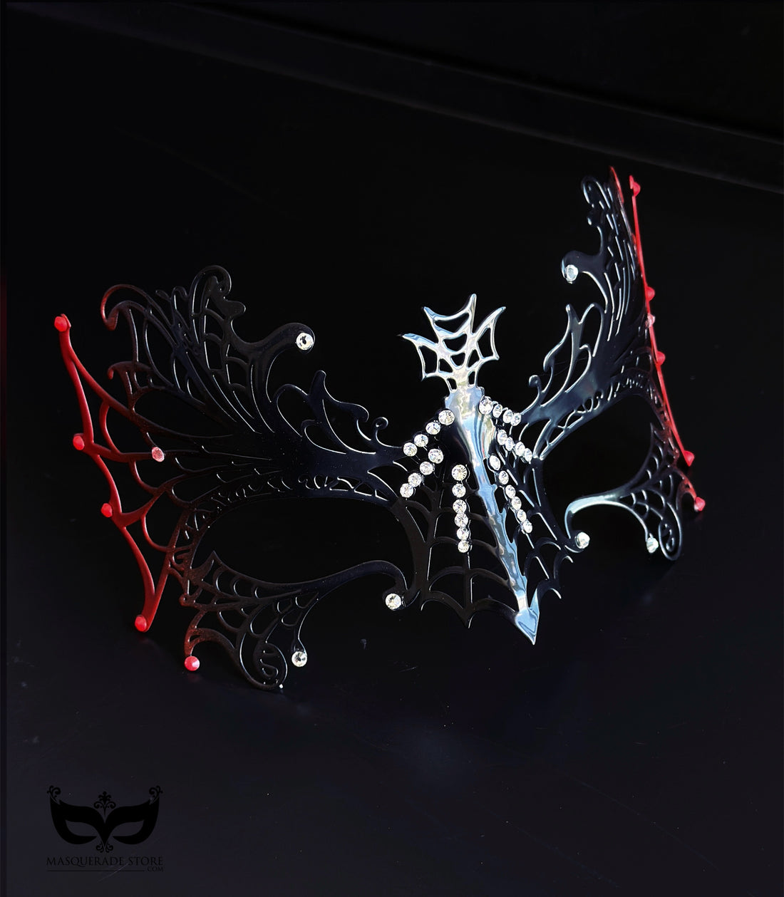 Red and black spiderweb masquerade mask with gothic openwork filigree, rhinestone accents, red web edges, and ribbon ties for costume events.