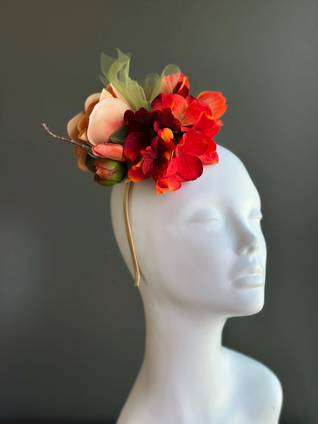 Peach and red floral fascinator hat with magnolia bloom for derby and wedding events.