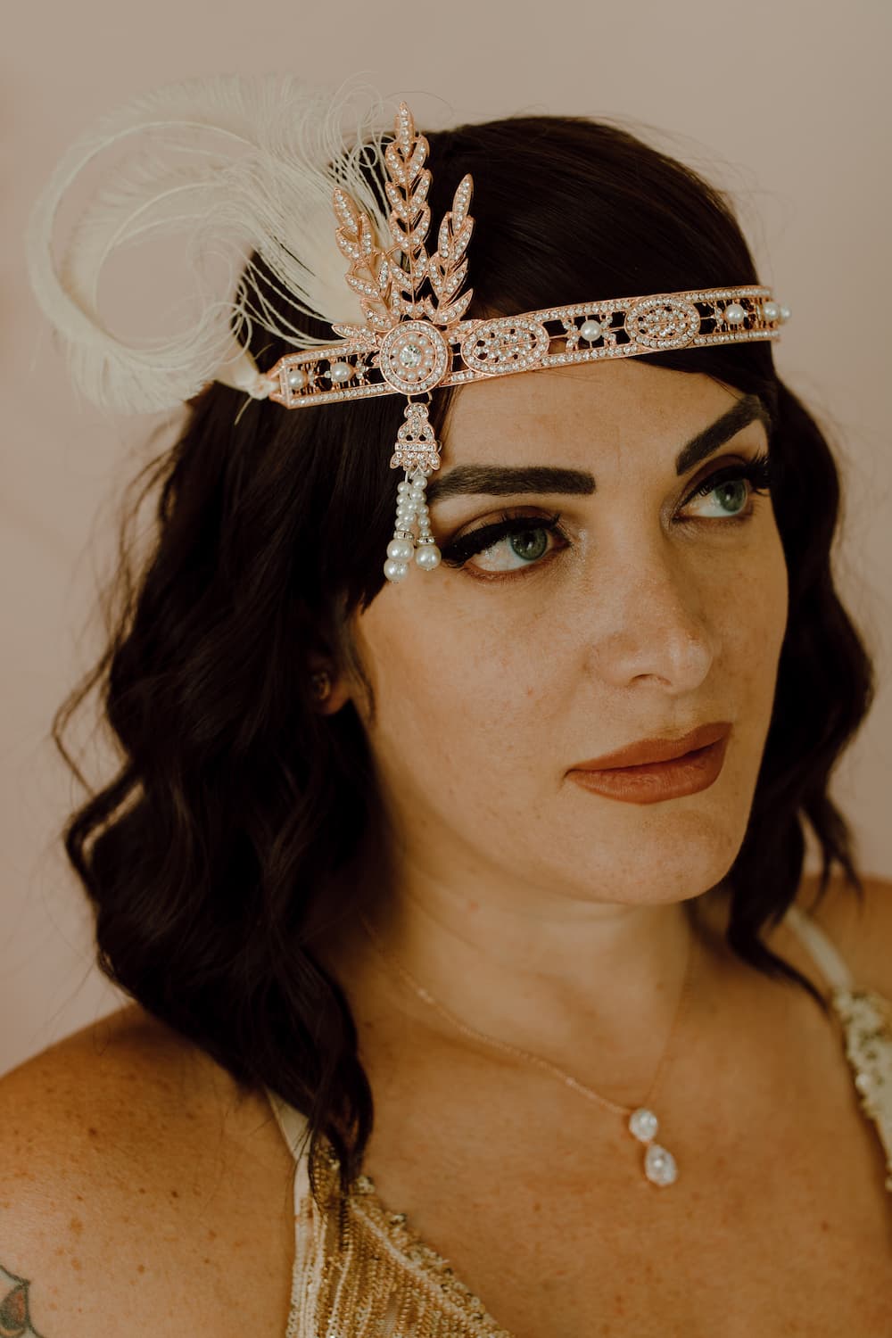 1920s-inspired rose gold feather headband with beaded fringe and art deco design