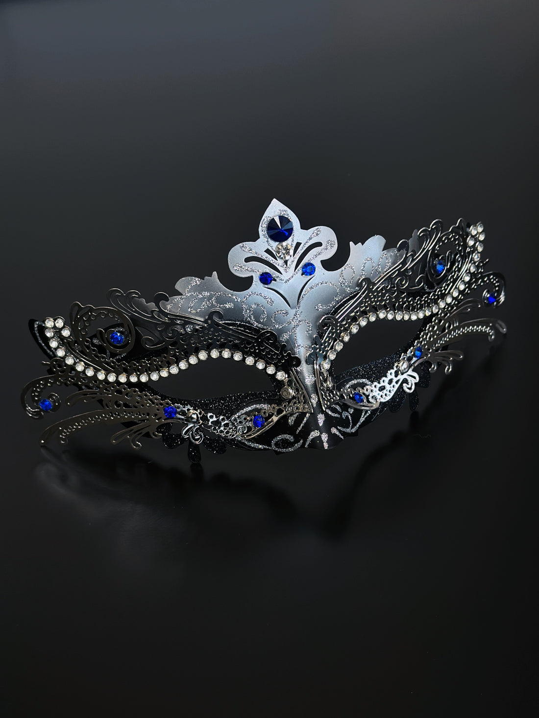 Silver masquerade mask with ornate filigree, rhinestones, and sapphire blue gems, perfect for women at Venetian masquerade balls, Mardi Gras, and parties.