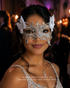 Silver Butterfly Whisper lace masquerade mask with embroidered butterfly-style lace, white floral side accents, rhinestone details, and bridal styling.