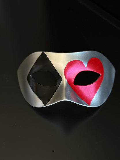 Silver casino masquerade mask with black diamond and red heart playing card motifs on Venetian eye-mask silhouette
