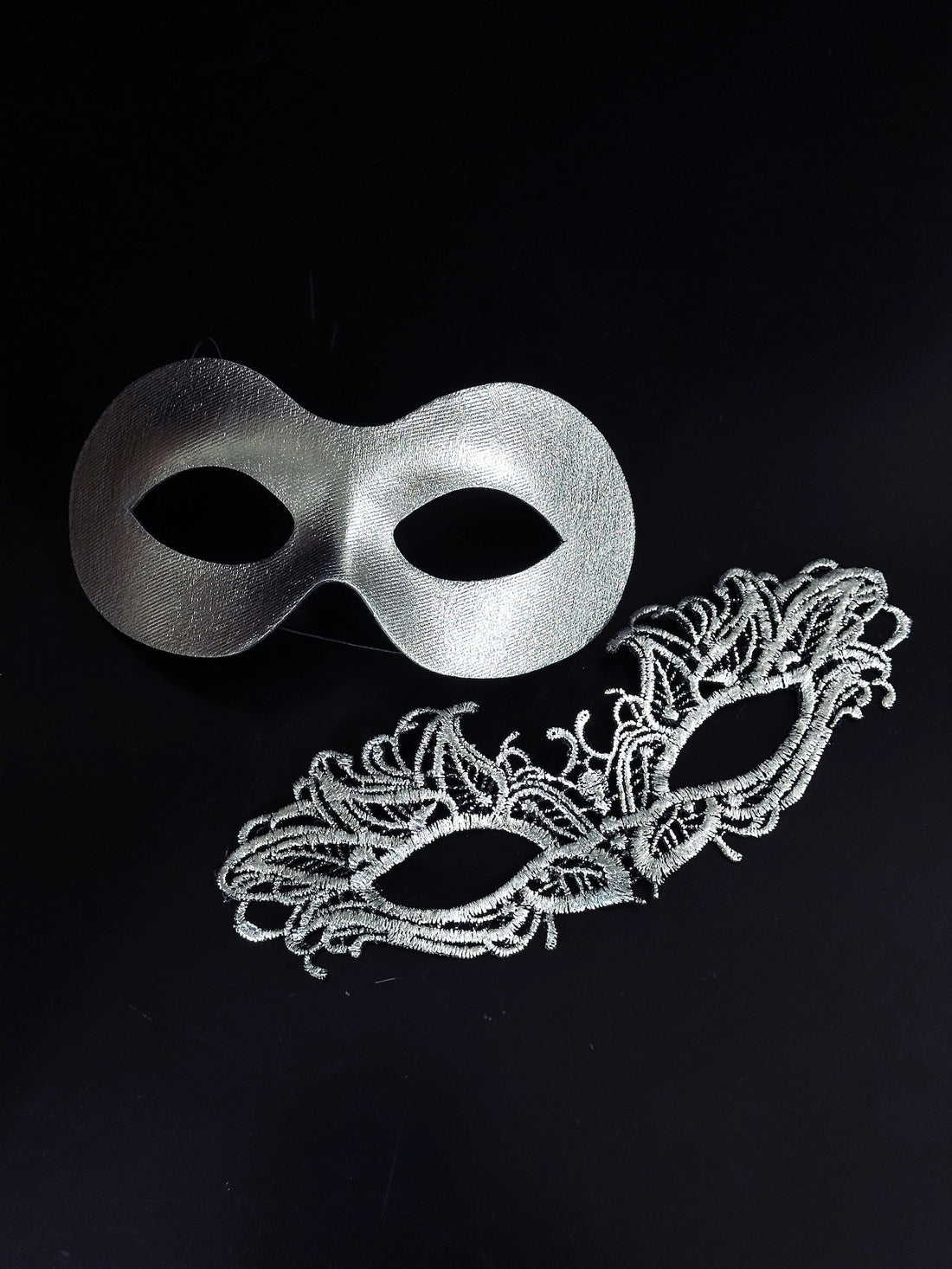 Elegant silver couples masquerade masks featuring a sleek metallic men’s mask and a delicate lace women’s mask, perfect for Venetian balls, weddings, and formal celebrations.