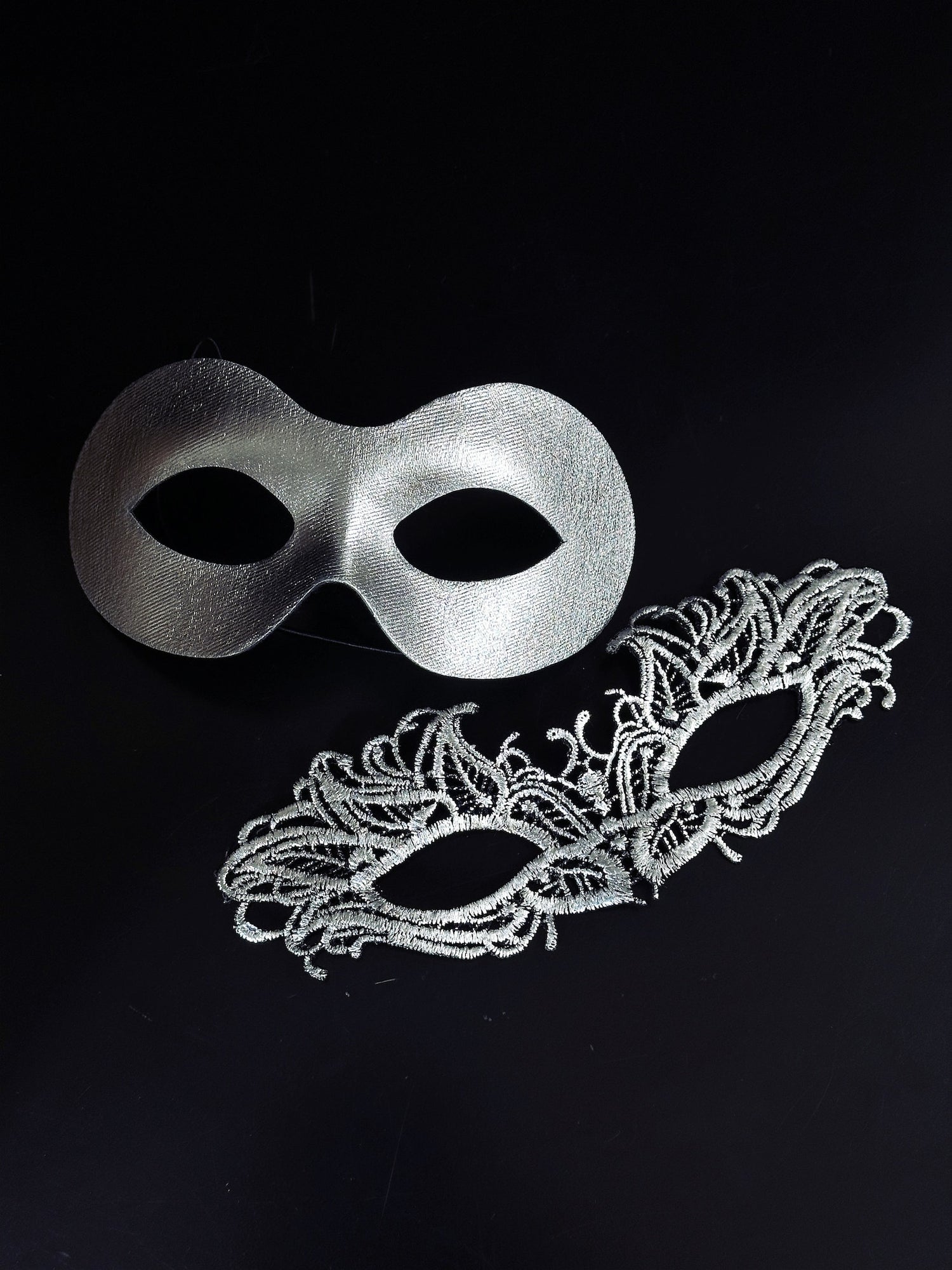 Elegant silver couples masquerade masks featuring a sleek metallic men’s mask and a delicate lace women’s mask, perfect for Venetian balls, weddings, and formal celebrations.