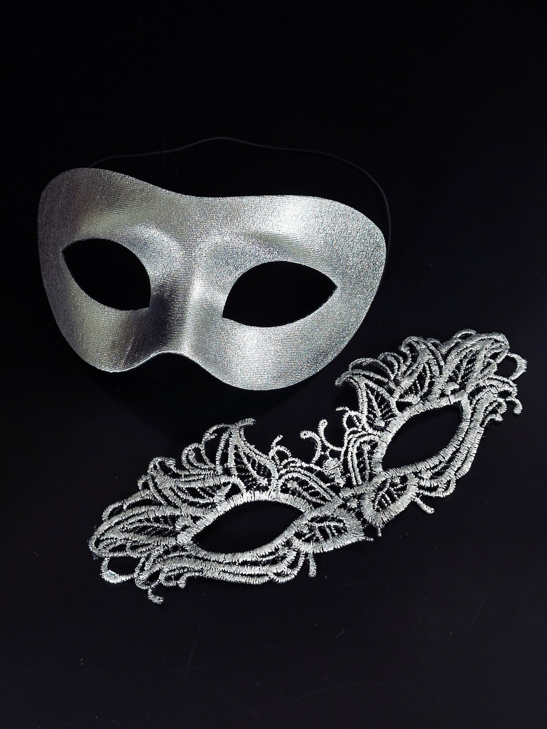 Silver metallic couples masquerade masks featuring a sleek men’s mask and a delicate lace women’s mask, ideal for Venetian balls, weddings, and formal celebrations.