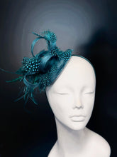 Teal feather fascinator hat with spotted accents, elegant headpiece for weddings and races.