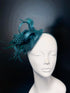 Teal feather fascinator hat with spotted accents, elegant headpiece for weddings and races.