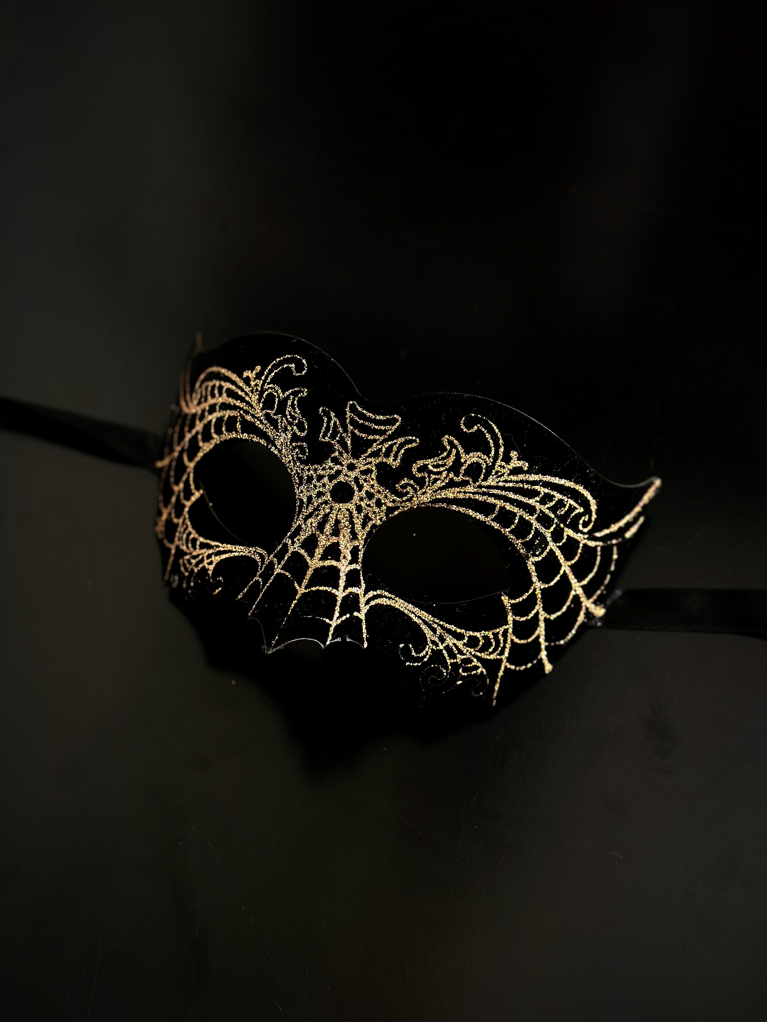 Unisex masquerade mask in black with a gold design.