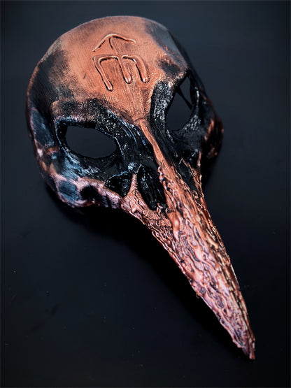 Crow masquerade mask hand painted in copper and black with a norse rune on the forehead.