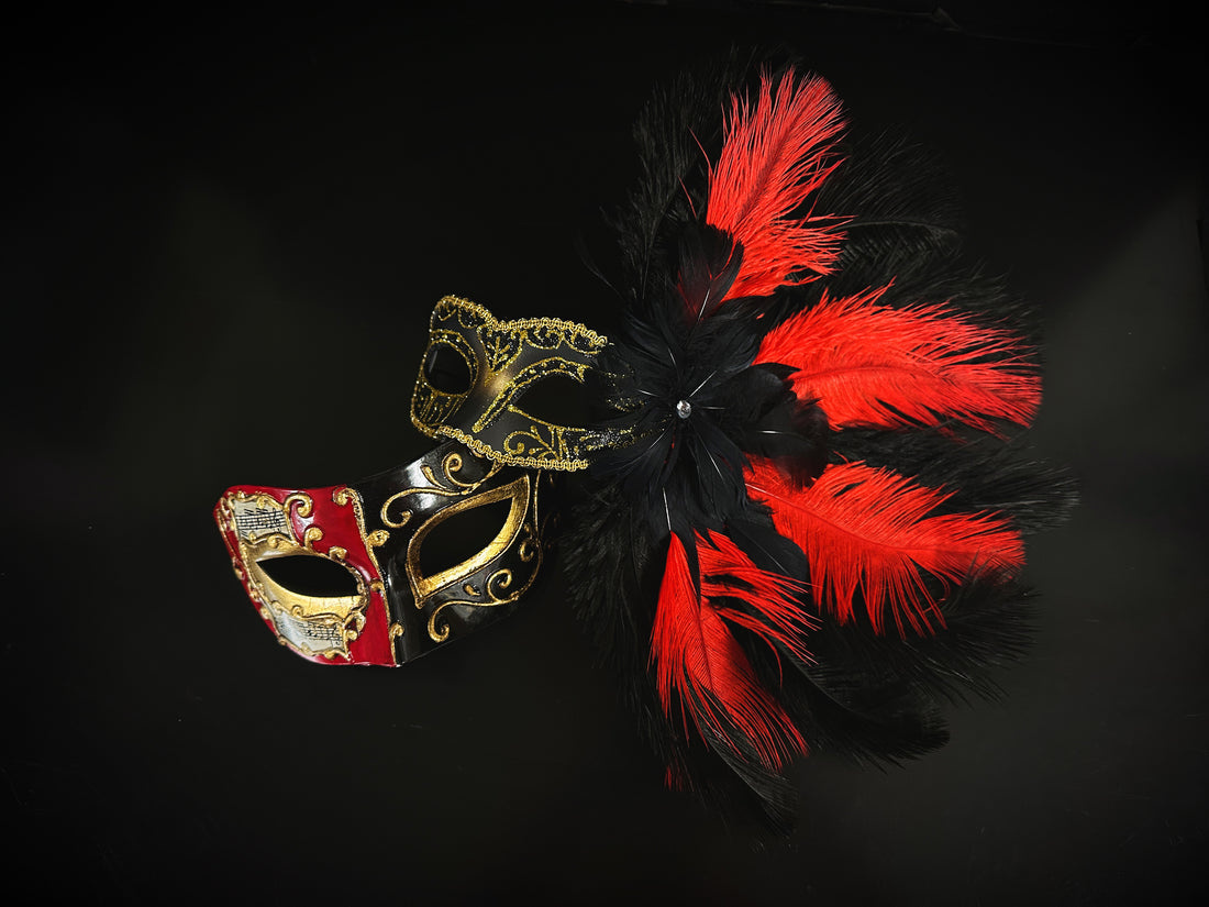 Venetian masquerade mask with red and black feathers, gold scrollwork, and music note accents.
