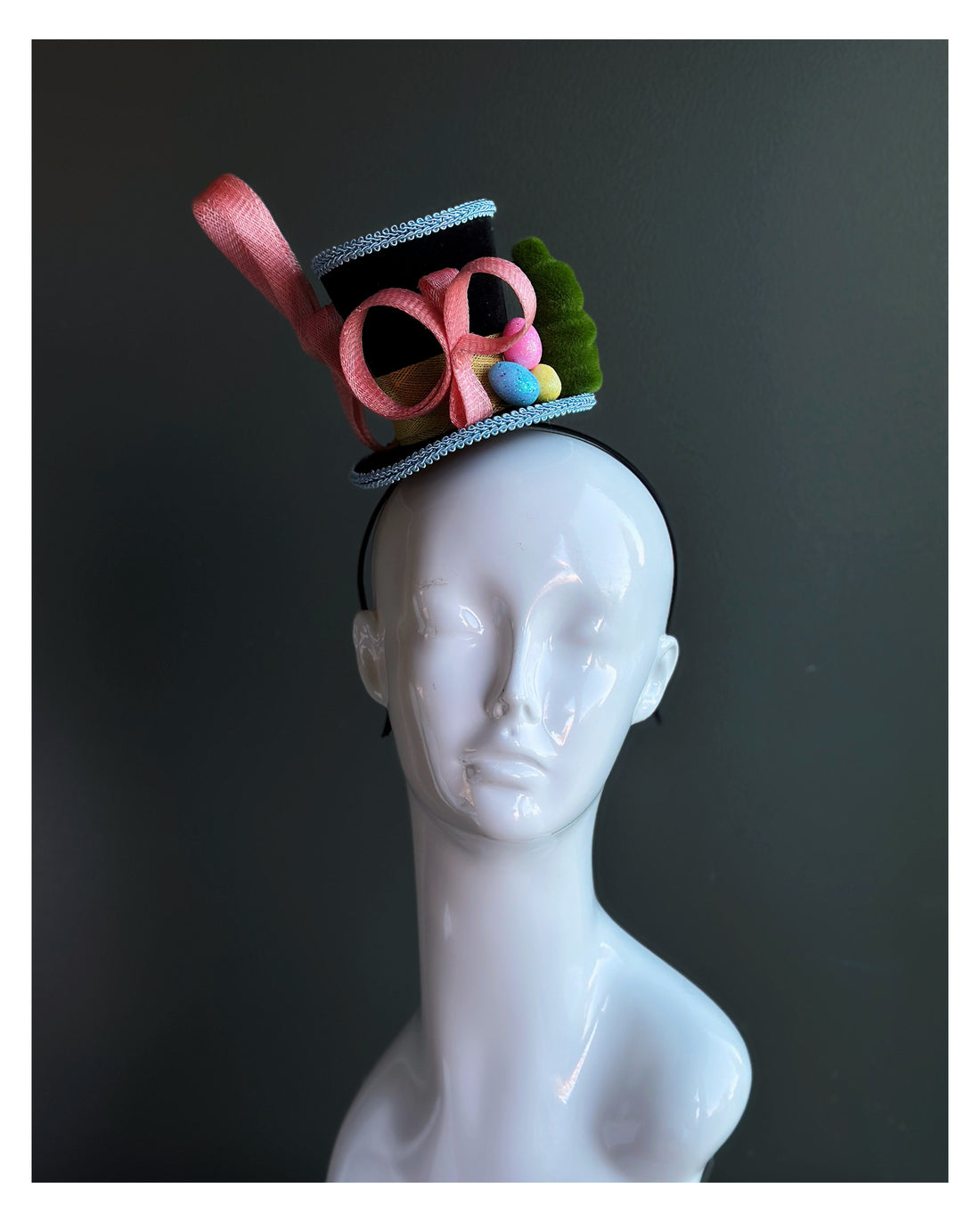 Whimsical mini top hat fascinator for women with a light blue trim, pink sinmay design and eater egg decorations 