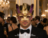 Purple, gold, and ivory jester masquerade mask with three-point harlequin crown, ornate scroll patterns, braided trim, and gold bell.