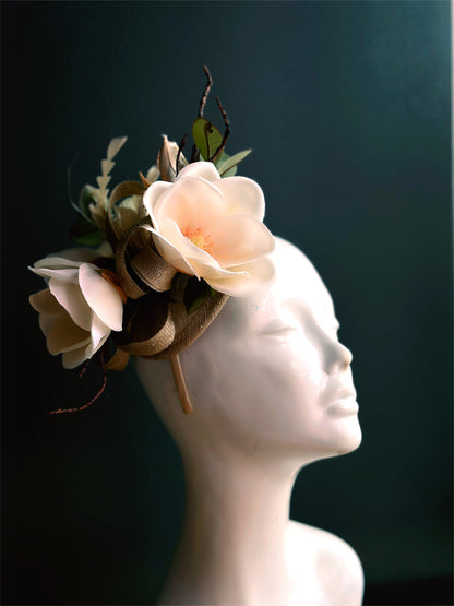 Fascinator tea party hat with magnolia flowers on a tan base.