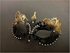 Women’s black and gold masquerade mask with rhinestone accents and ornate filigree design.