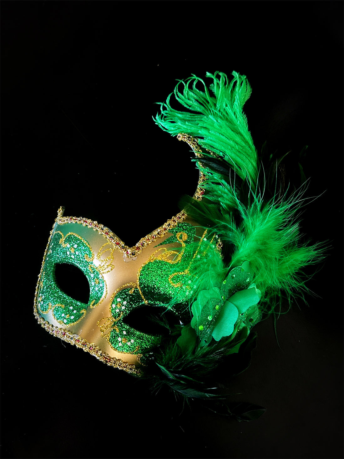 Womens masquerade mask in gold and green with green feathers.