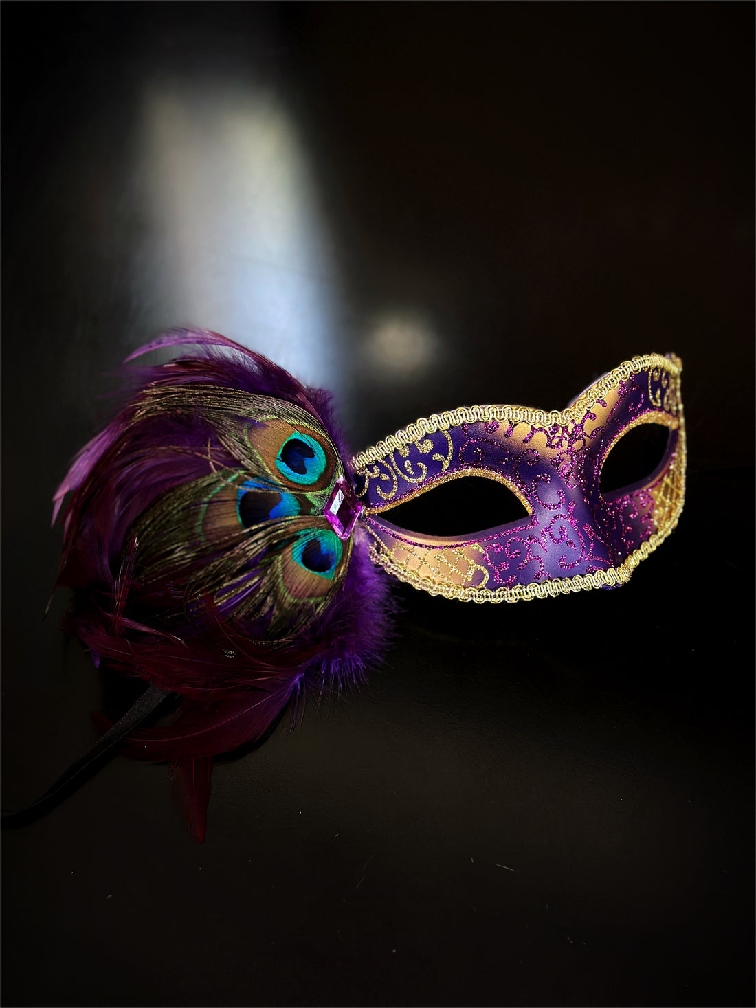 Womens masquerade mask in purple and gold with peacock feathers.