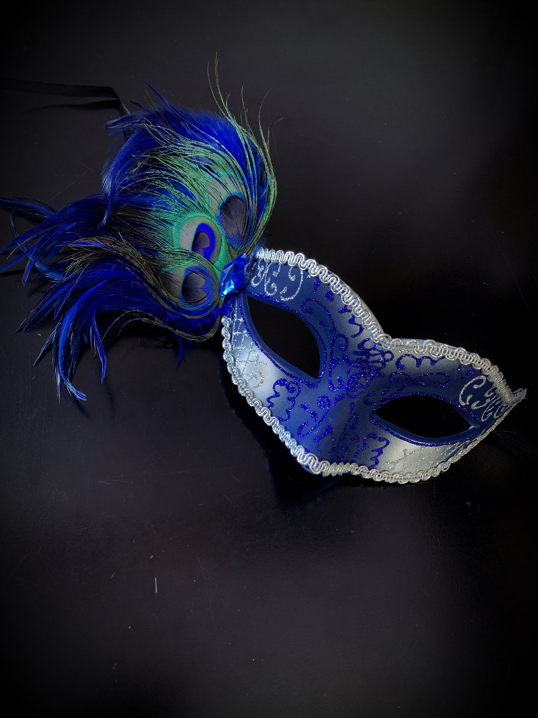 Womens masquerade mask on a blue silver base with peacock feathers.