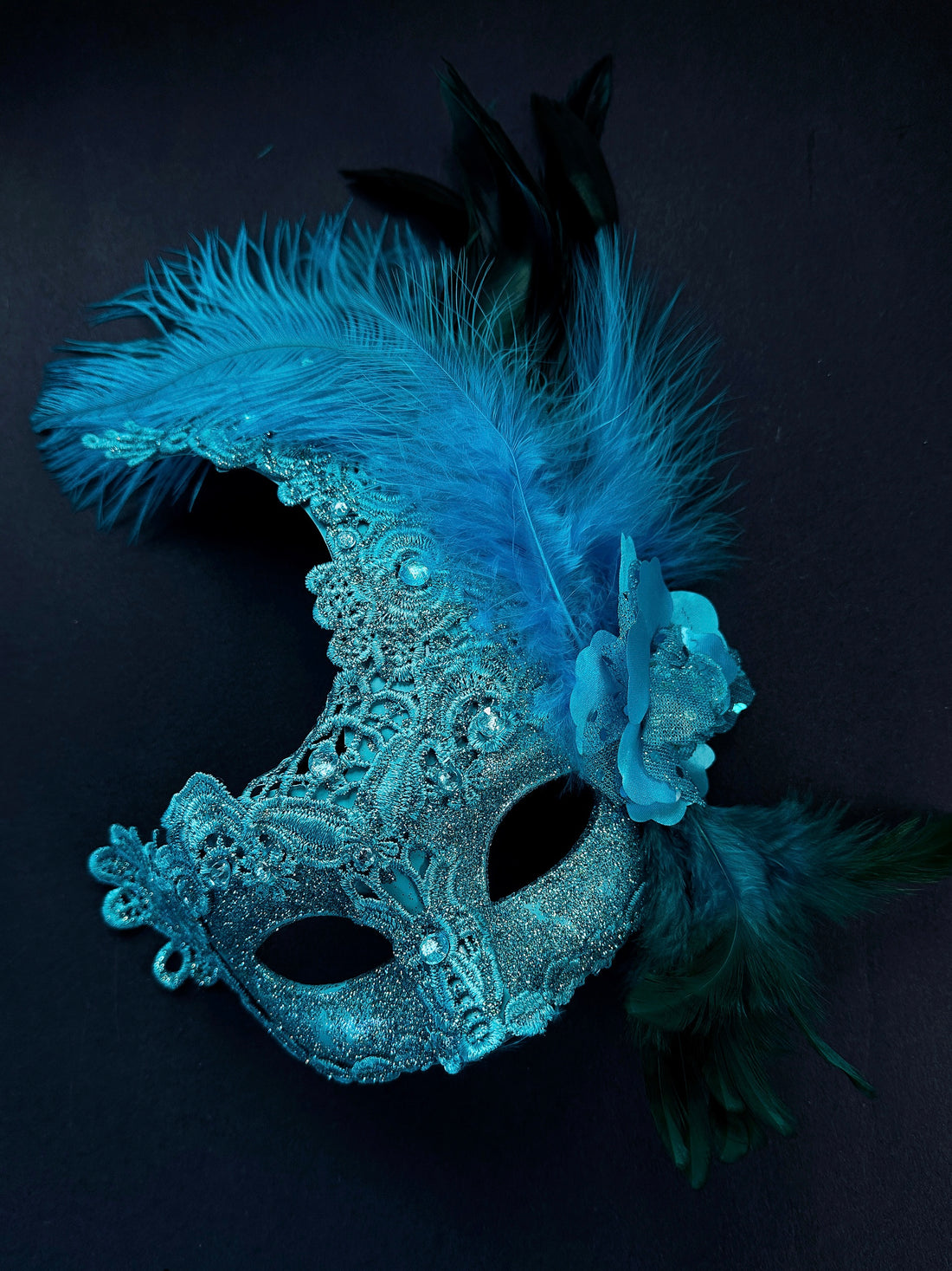 Turquoise glitter lace masquerade mask for women with feathers, rhinestones, and rose flower detail.