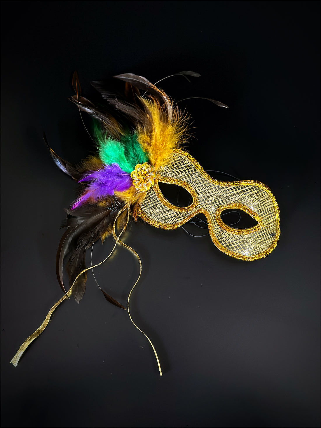 Womens masquerade mask in gold with purple, gold, and green feathers.