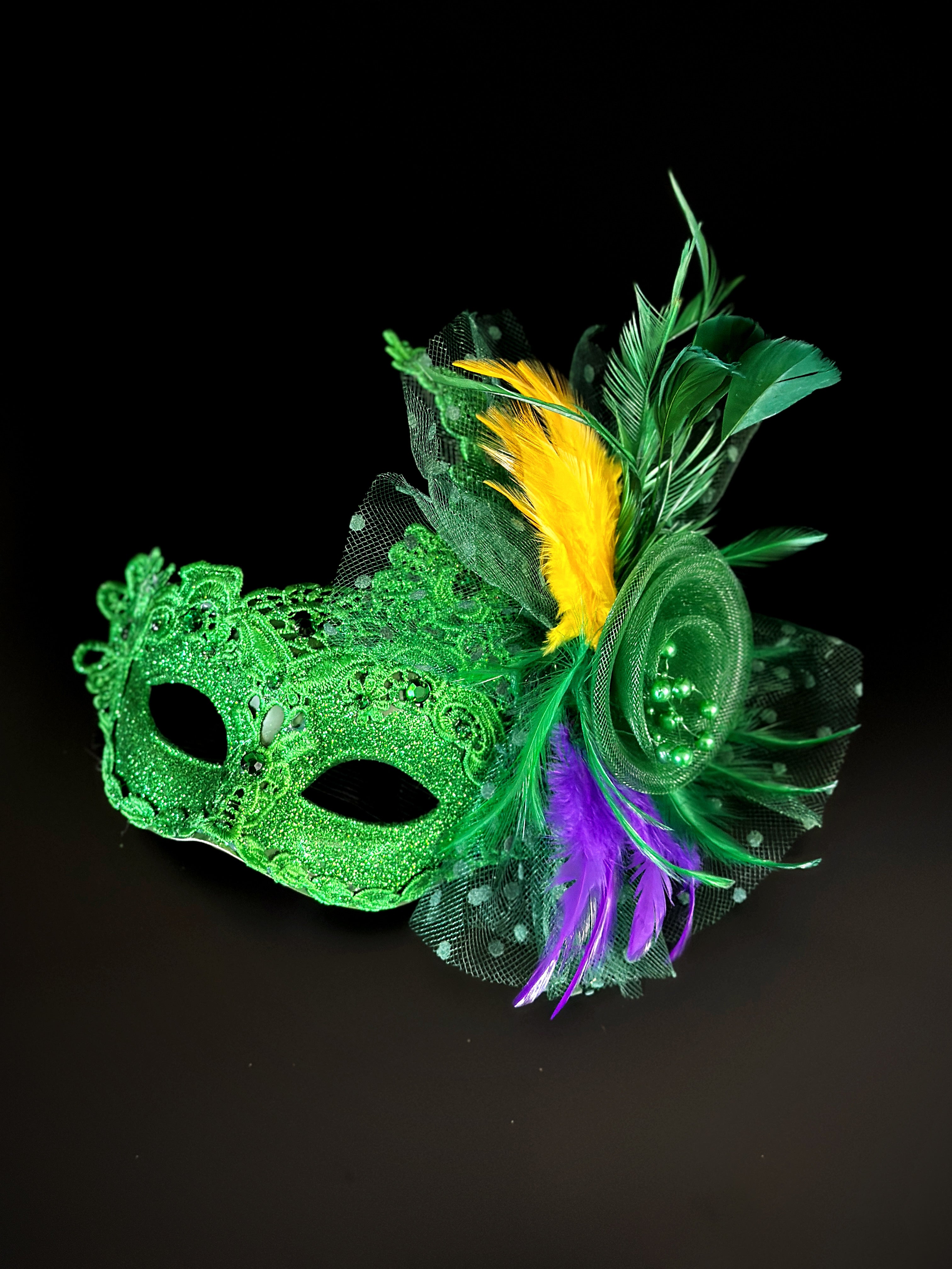 Womens masquerade mask in green with purple and yellow feathers.