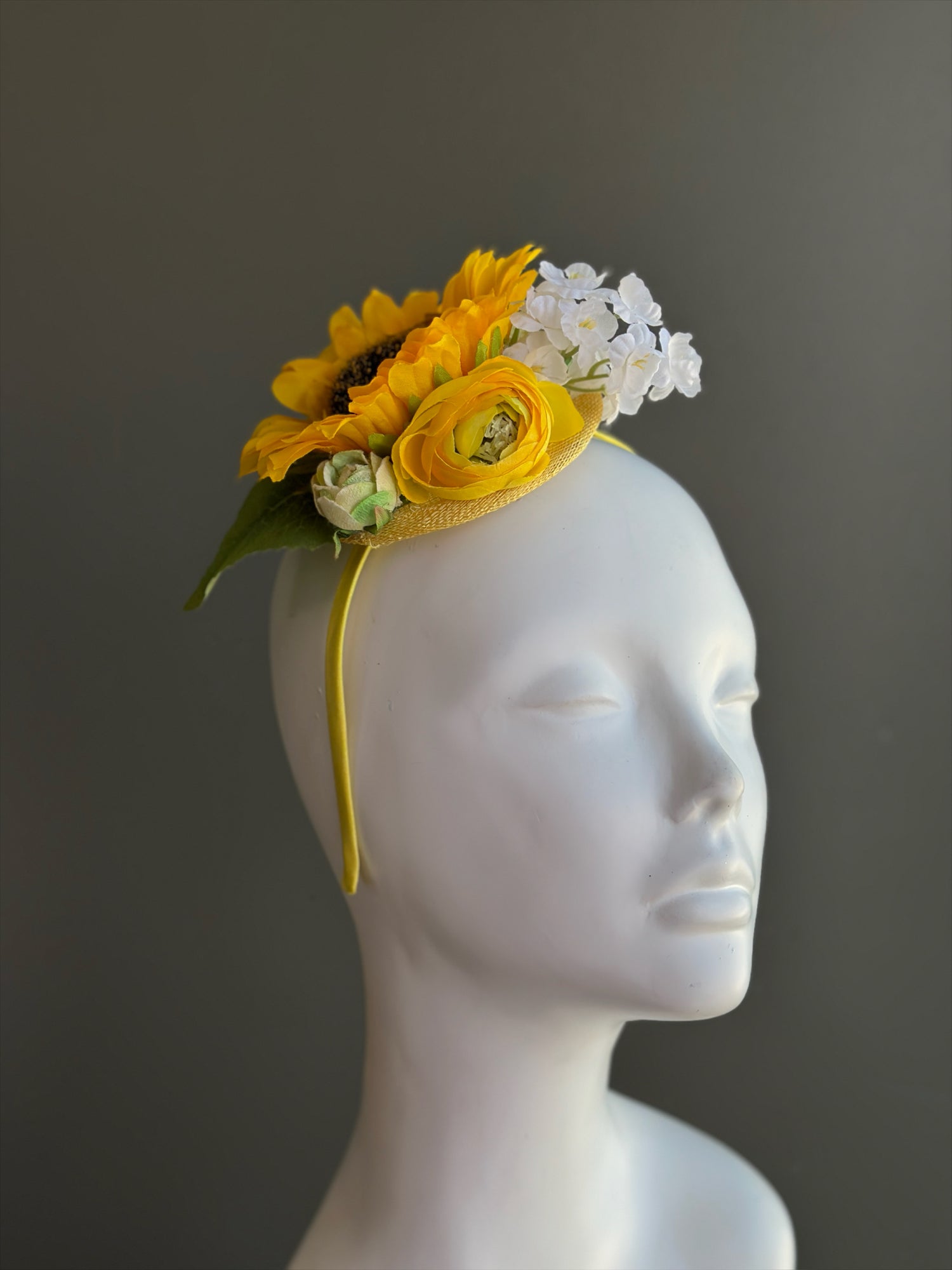 Yellow sunflower fascinator hat with ranunculus and white flowers for derby and wedding events.