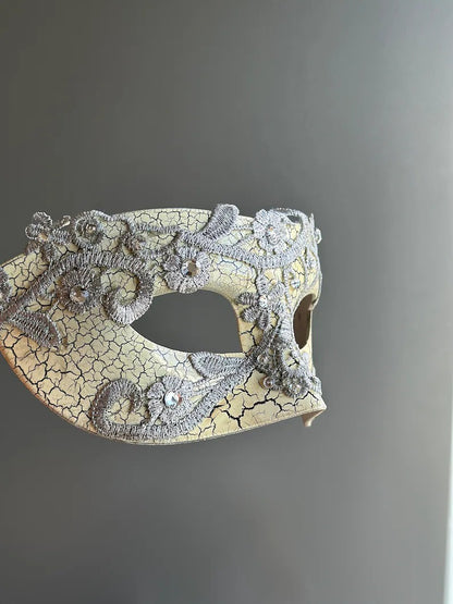 Side view of antique crackle Venetian masquerade mask with silver lace and rhinestone accents.