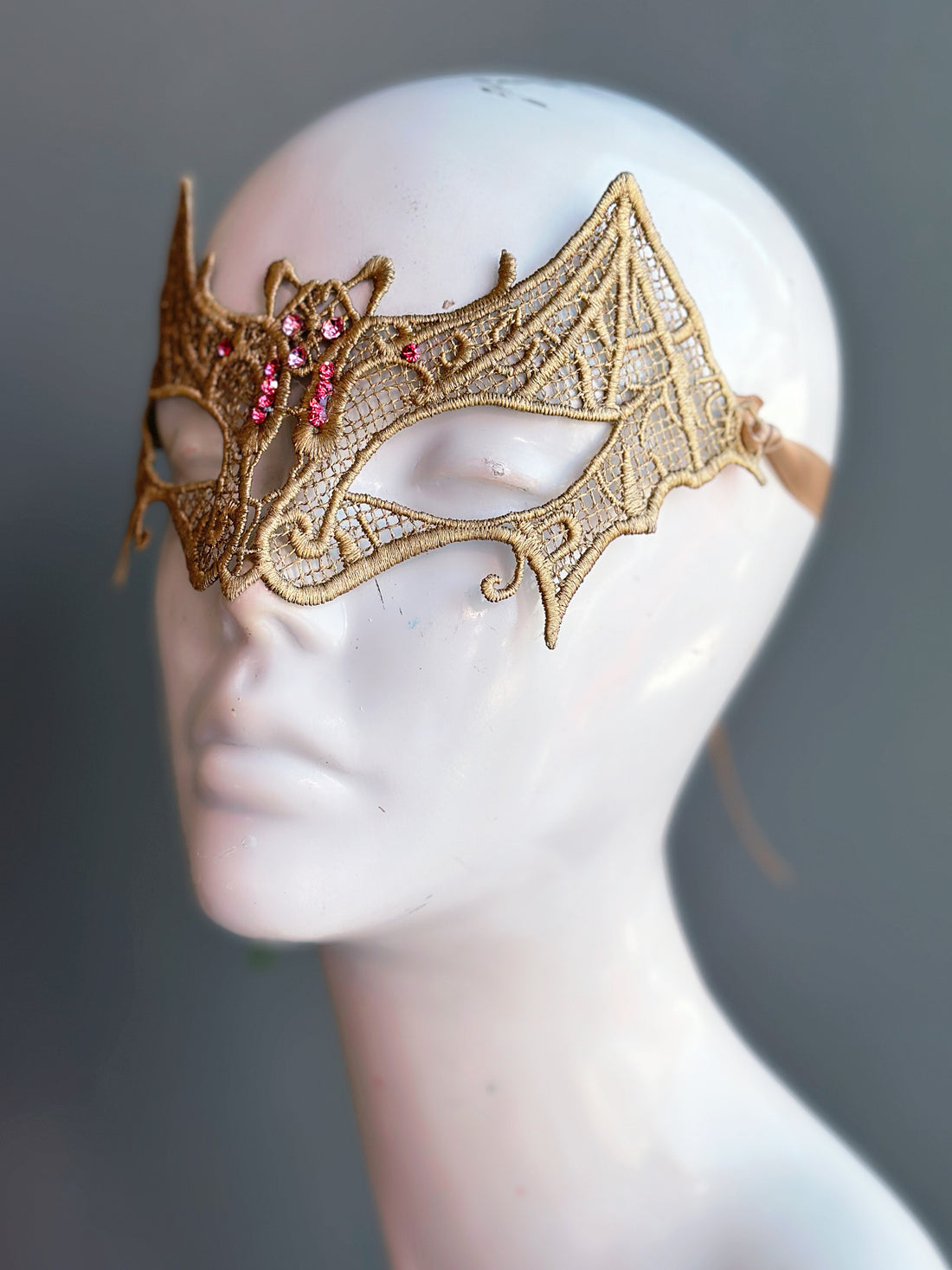 Gold lace mask in bat silhouette, with pink rhinestones