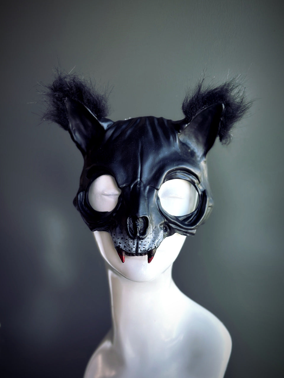 Black cat mask with furry ears, sculpted details, and small fangs, perfect for Halloween and gothic masquerade events.

