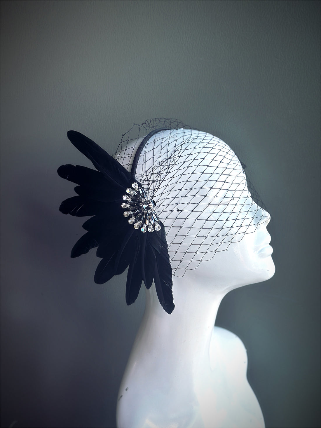 "Black feather fascinator with a crystal accent and a delicate mesh veil, perfect for weddings and vintage-themed events."